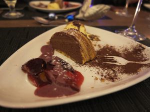 Café Schokoladenmousse im Baumkuchen, serviert mit Erdbeeren/Pflaumen und geeister Pecan-Nuss